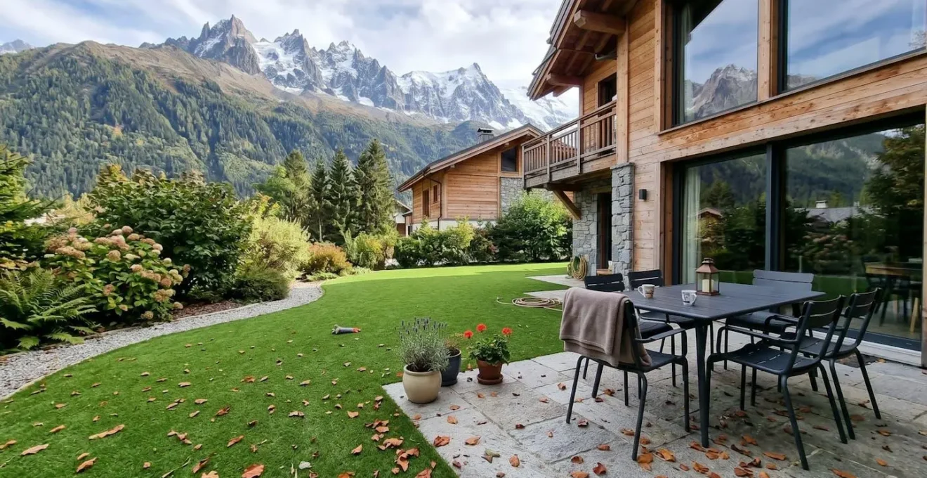 Jardin impeccable d'une résidence secondaire avec gazon verdoyant et terrasse aménagée en arrière-plan montagneux